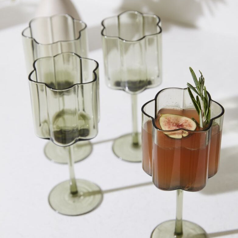 Four Sonnet Smoky Green Stemmed Wine Glasses, one filled with an deep orange cocktail garnished with fig and rosemary.