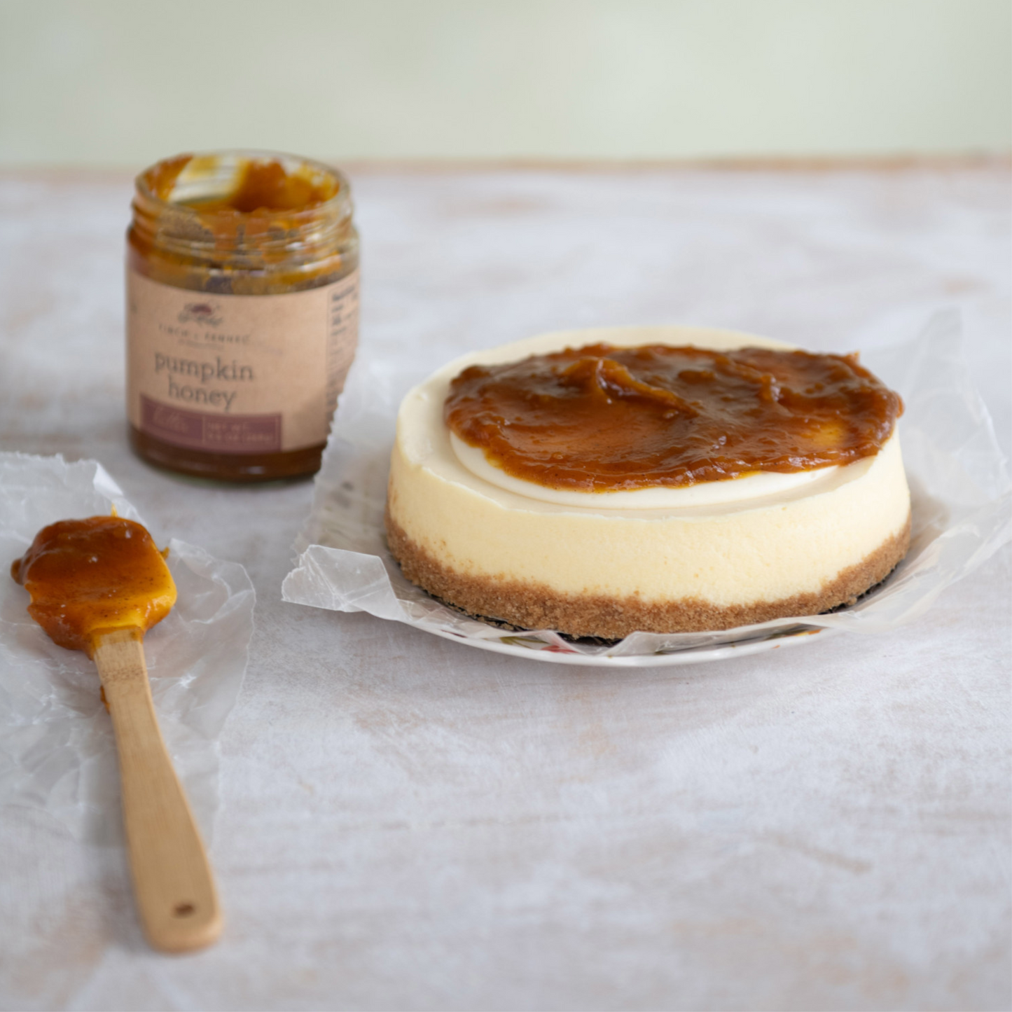 Pumpkin Honey Butter in a glass jar shown spread on cheesecake, great for gifting, a holiday favorite