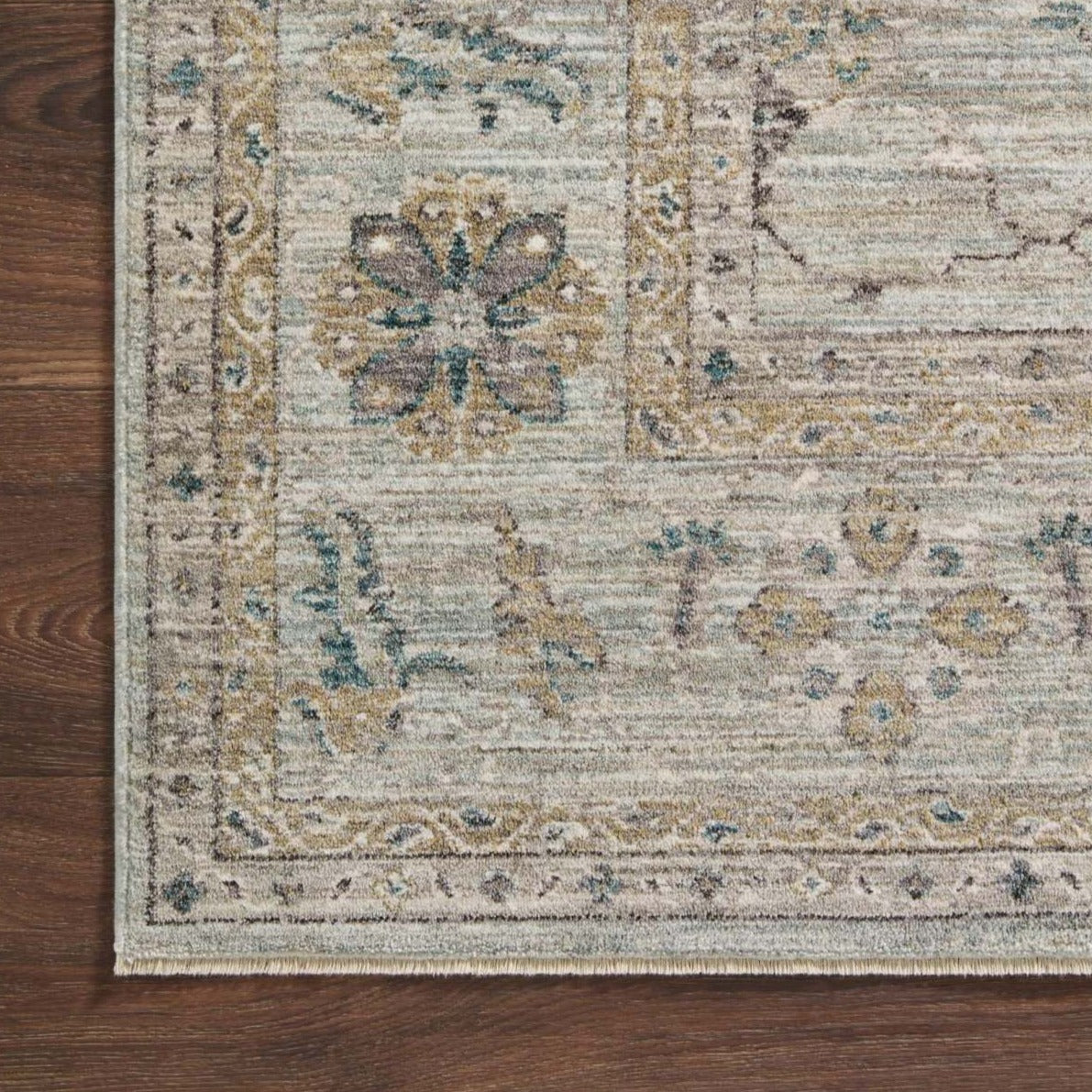 Cambria Soft Blue Rug with Gold Accents on Wood Floor