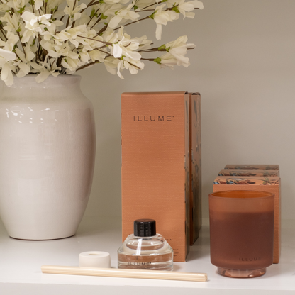 Terra Tabac Fragrance Diffuser and Candle Next to White Cache Pot Vase with Faux Florals